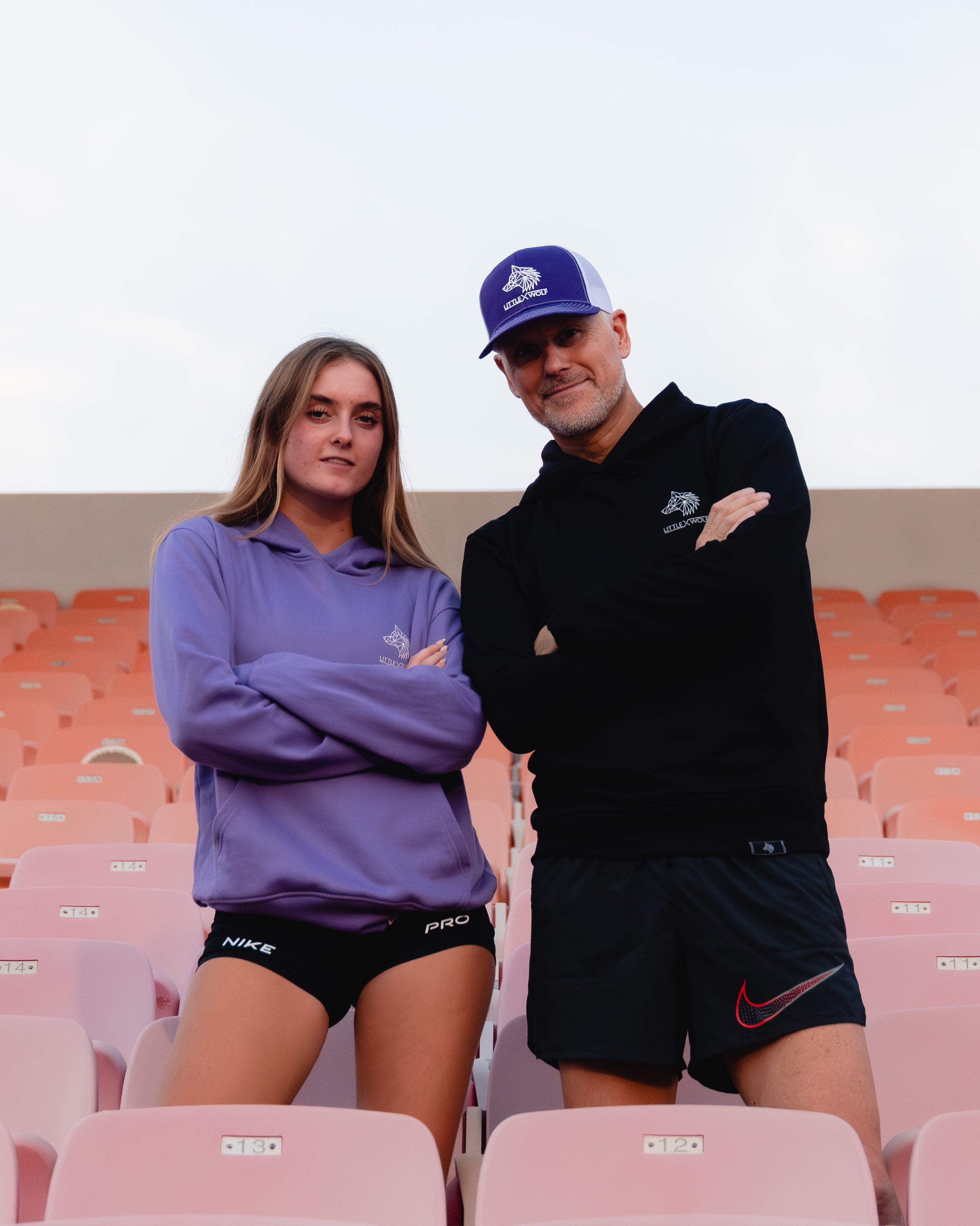 Two people standing in an empty stadium with a plain background